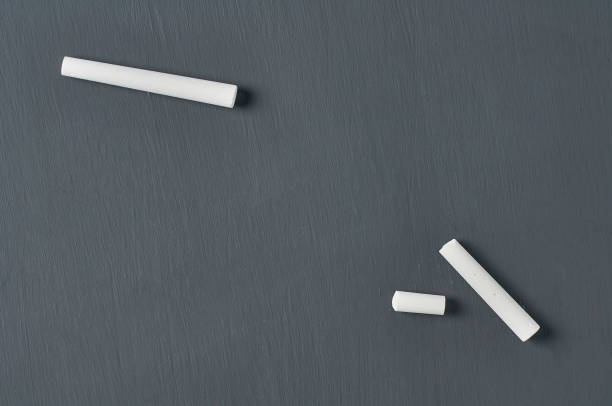istock One white broken piece of chalk on black chalkboard. Copy space. Flat lay 1204871890