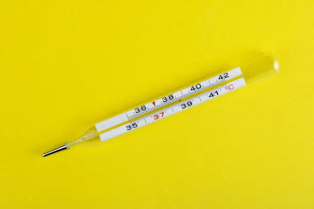 Photo of Medical device thermometer isolated on a yellow background. High temperature. Medical device. The concept of medicine. Copy space