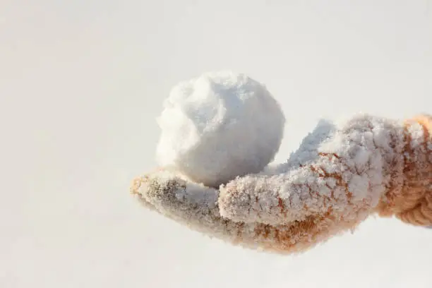 The hand of a baby girl holds snow for a game.