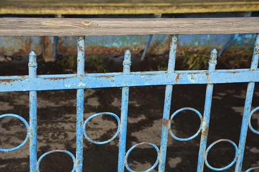 blue metal texture from old iron bars in a forged pattern in the wall of a fence on the street