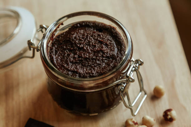 istock Homemade chocolate paste in a glass jar and hazelnuts on a wooden table. 1204887058