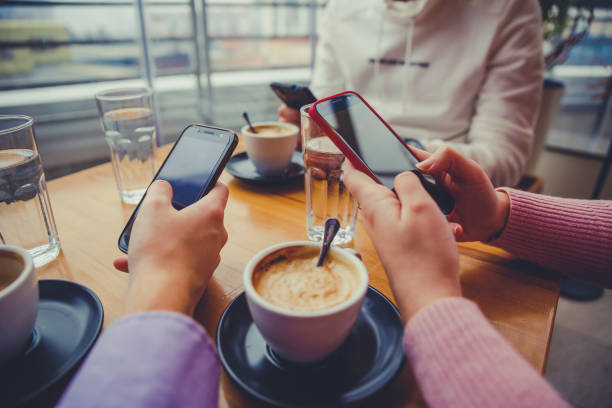 istock Friends in cafe using mobile phones 1204889391