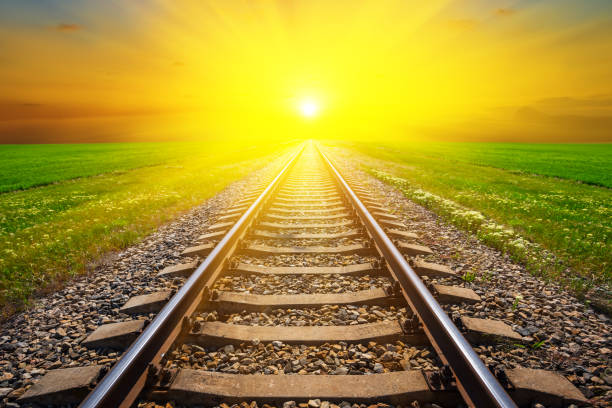istock railway among green fields leaving far to a sunset 1204890718