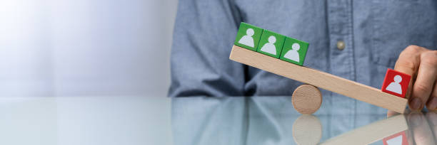 istock Balancing Pawns On Wooden Seesaw 1204893754
