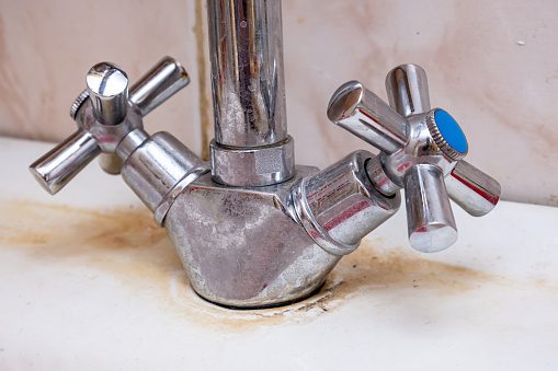 Detail of faucet with limescale or lime scale on it, dirty calcified and rusty kitchen mixer tap, close up.