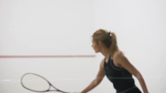 Young athletic man and woman play squash together in the squash court, slow motion, close up shot