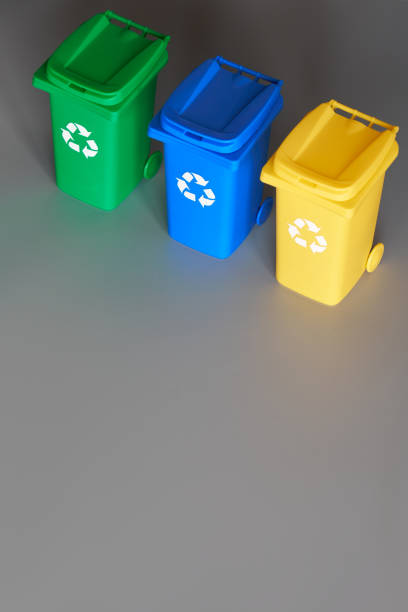 istock Three color coded recycle bins, isometric picture on grey paper, copy-space. Recycling sign on the bins, blue, yellow and green. Waste separation to reduce mixed waste and recycle paper and plastic. 1204899009