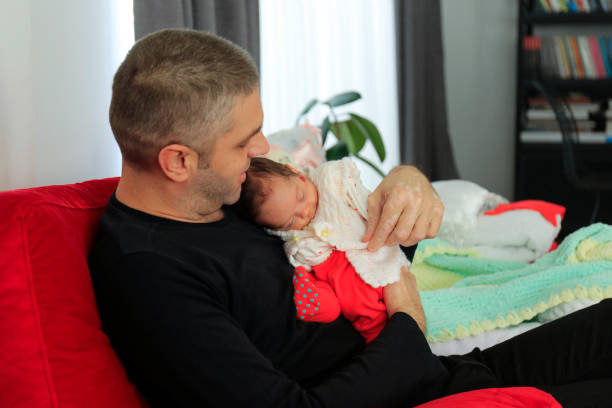 A newborn baby holding a boy's finger