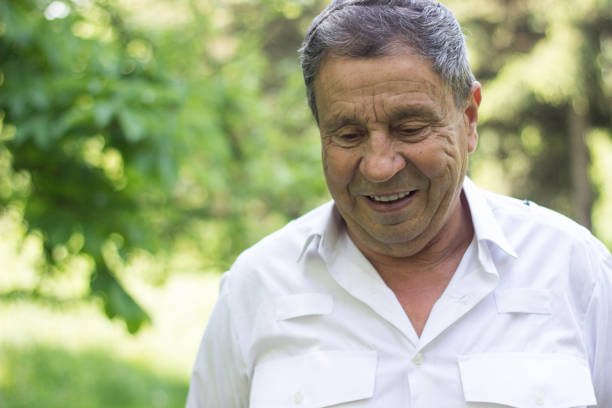 Portrait of a smiling senior man in Nature, looking down