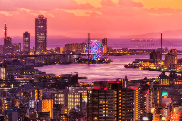 Red colourful sunset in Osaka city over sea horizon from the top of skydeck skyscraper tower towards sea port terminal and ships.