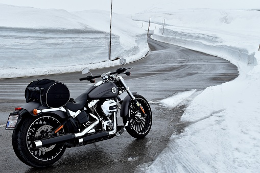 Innsbruck / Austria - May 31 2019 - Motorbike parked on road side which is cleared from high snow