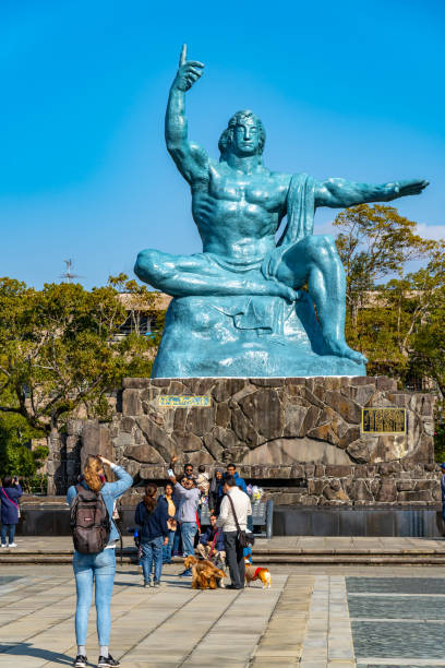 turista tomando fotos en la estatua de la paz en el parque de la paz de nagasaki - war globe symbols of peace weapon fotografías e imágenes de stock
