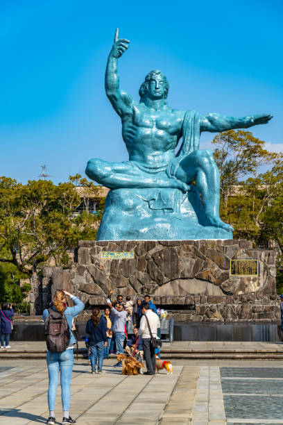 turista che scatta foto sulla statua della pace nel parco della pace di nagasaki - war globe symbols of peace weapon foto e immagini stock