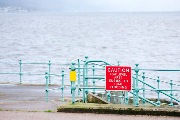 istock Low tide area subject to tidal flooding warning sign at harbour wall 1204916249