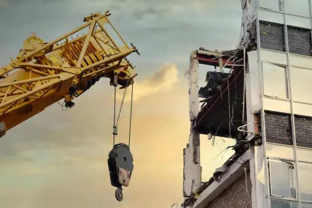 Crane lifting hook at construction site with derelict building for demolition uk