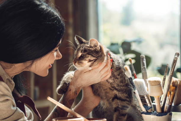 istock Craftsperson Concept. Young female artisit at creative studio sitting stroking cat smiling happy close-up 1204923429
