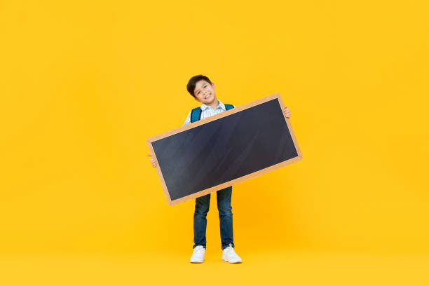 Smiling handsome 10 year-old mixed race boy holding empty blackboard