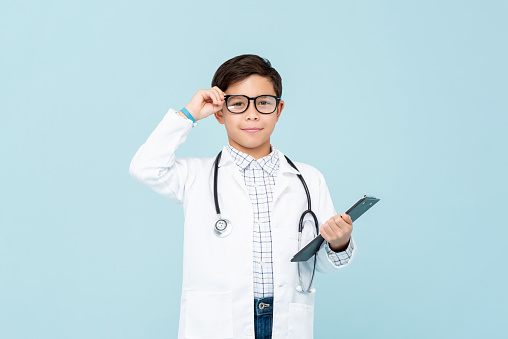 Niño médico inteligente sonriente con abrigo médico blanco y estetoscopio photo