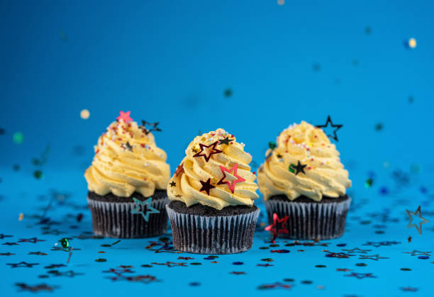 cupcakes mit gelbem sahnehäubchen verziert mit konfetti und streuseln - back to front ideas surrealism concepts stock-fotos und bilder
