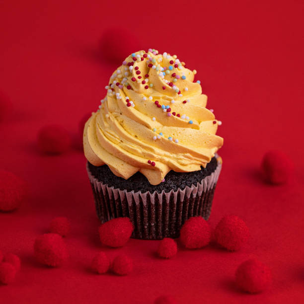 Yellow muffin besprent with edible sprinkles ornate with red pom poms