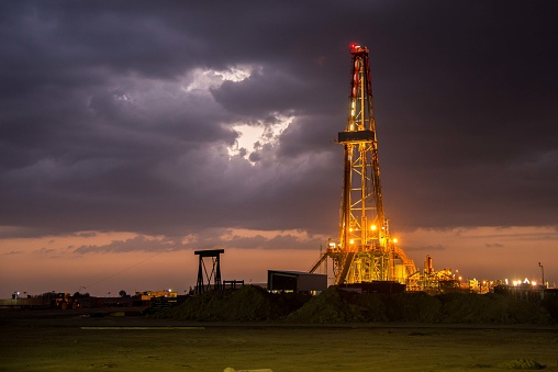 Drilling rig at night with sky clouds