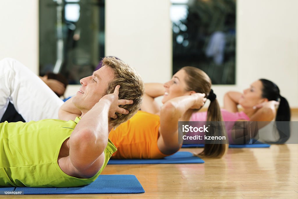 Man and women doing sit-ups at a gym for fitness People, man and women, exercising doing sit-ups in gym or fitness club  Abdominal Muscle Stock Photo