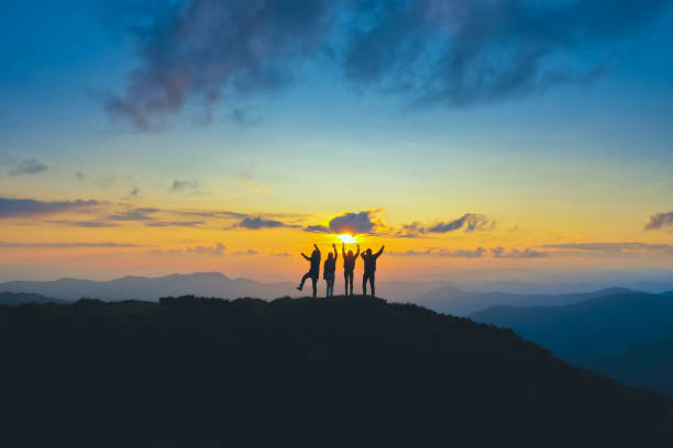 Photo of The four people standing on the beautiful mountain on the sunrise background