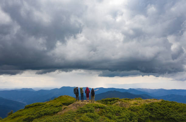 istock The four active people standing on the mountain against beautiful clouds 1204930414