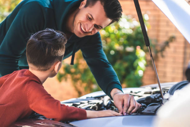 istock The father and son fixing under the car hood 1204931090