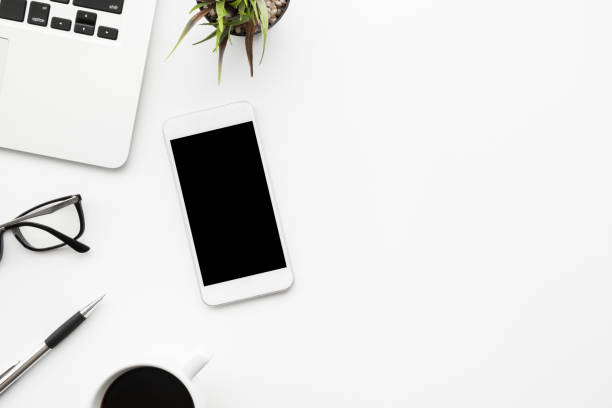 istock White smartphone with black blank mock up screen is on top of white office desk table with supplies. Top view with copy space, flat lay. 1204937611