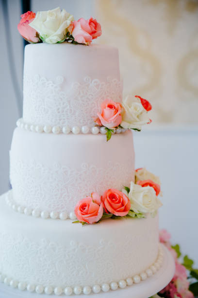 istock Three tiered wedding cake with fresh peach and pink roses 1204957188