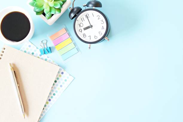 istock Top view of notebook, clock, pen and coffee cup on blue background with copy space ready for adding or mock up 1204959040