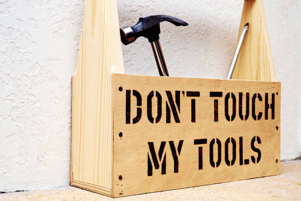istock An iron hammer and a screwdriver lie in a convenient wooden box for home tools. Stencil words scorched - don't touch my tools. Side view 1204964473