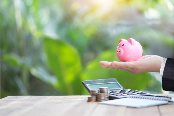 istock Pink piggy bank is placed on the hand with calculator and stack coin. 1204966655