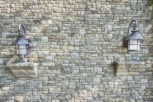 Street lantern hanging on grey stone wall.