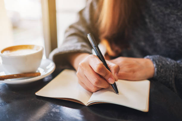 istock a woman writing on a blank notebook on the table 1204976707
