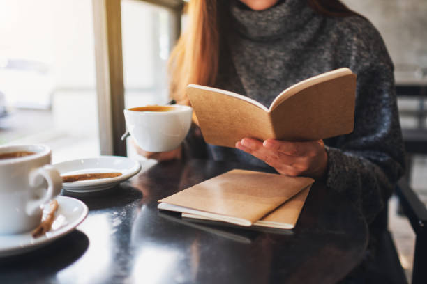istock a woman reading a book while drinking coffee in cafe 1204976744