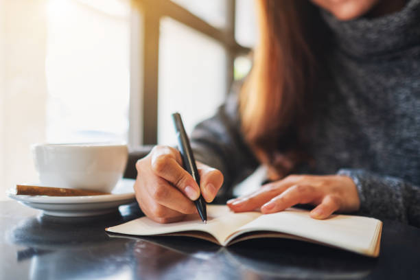 istock a woman writing on a blank notebook on the table 1204976851