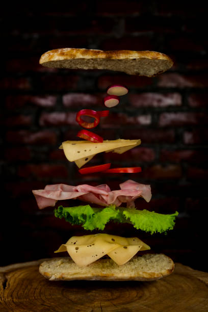 istock Sandwich with Flying Ingredients. Ham, Lettuce, Tomatoes ,Cheese, Peppers and Bun 1204983236