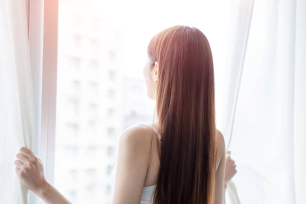 istock asian woman opening curtain 1204985400