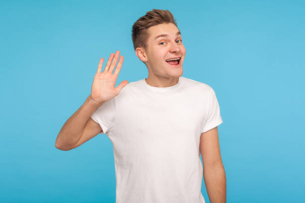 hallo, willkommen! porträt von lustigen glücklichen gastfreundlichen mann in lässigen weißen t-shirt winkenhand - human hand waving human arm high angle view stock-fotos und bilder
