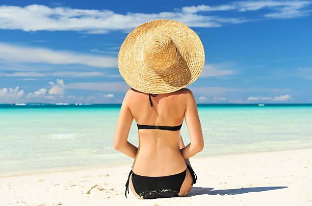 istock Girl in a wicker hat sitting on a beach 120499342