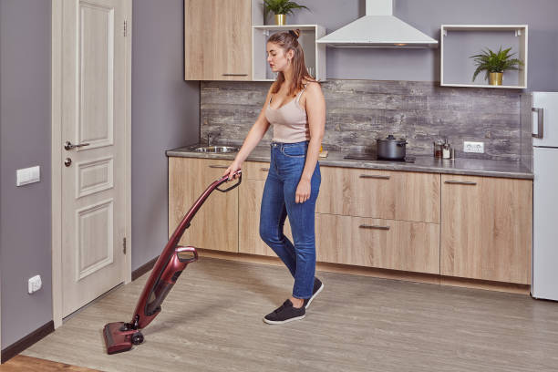 istock Young white maid is vacuuming floor in the kitchen 1204994670