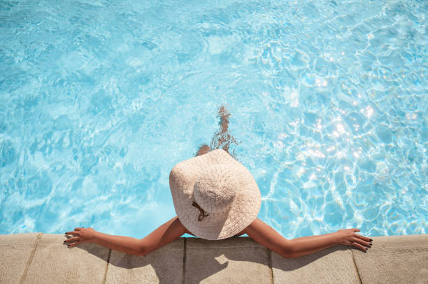 jeune femme détendant dans la piscine - bain de soleil photos et images de collection