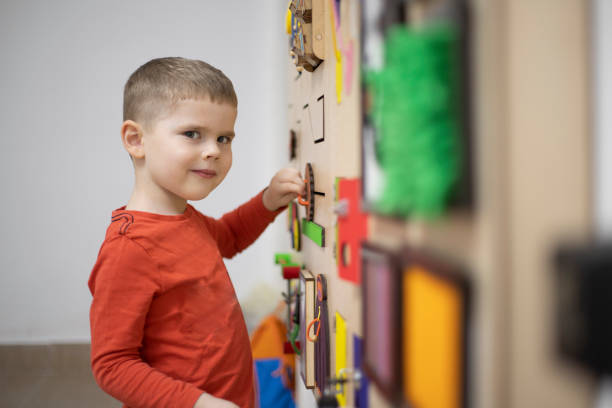Therapy Of playing Three years old boy playing on the busy board at his psychotherapy session. autism photos stock pictures, royalty-free photos & images