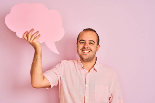istock Young man holding cloud speech bubble standing over isolated pink background with a happy face standing and smiling with a confident smile showing teeth 1204998889