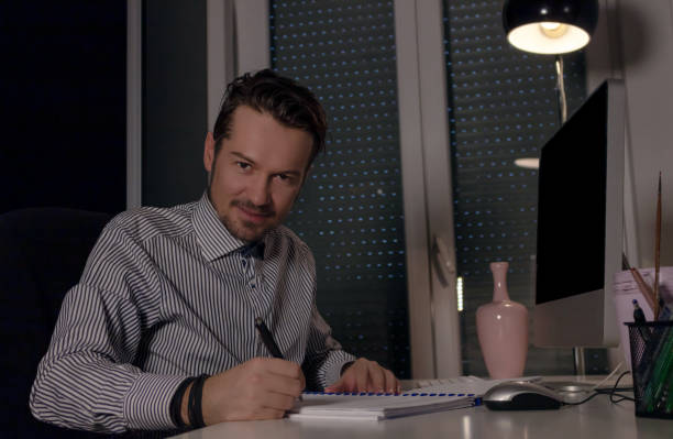 istock Happy businessman going through reports while working late in the office. 1204998929