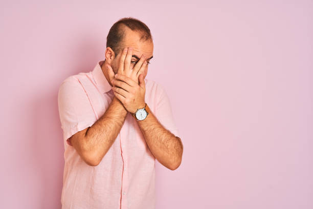 istock Young man wearing elegant shirt standing over isolated pink background with sad expression covering face with hands while crying. Depression concept. 1204999253
