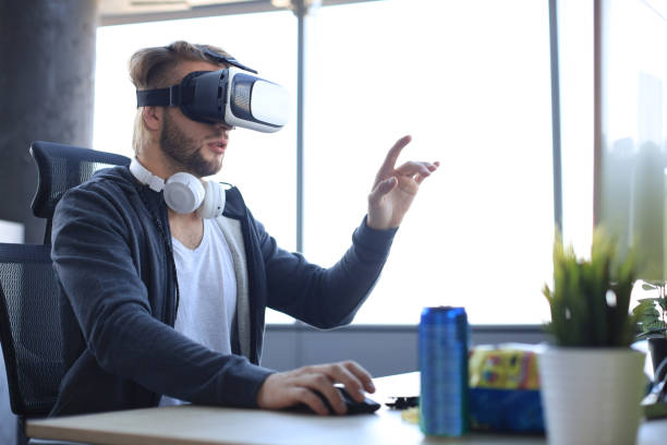 istock Young bearded man wearing virtual reality glasses in modern interior design coworking studio. 1204999474