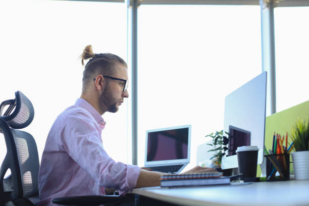 istock Thoughtful young business man in shirt working using computer while sitting in the office. 1205000592